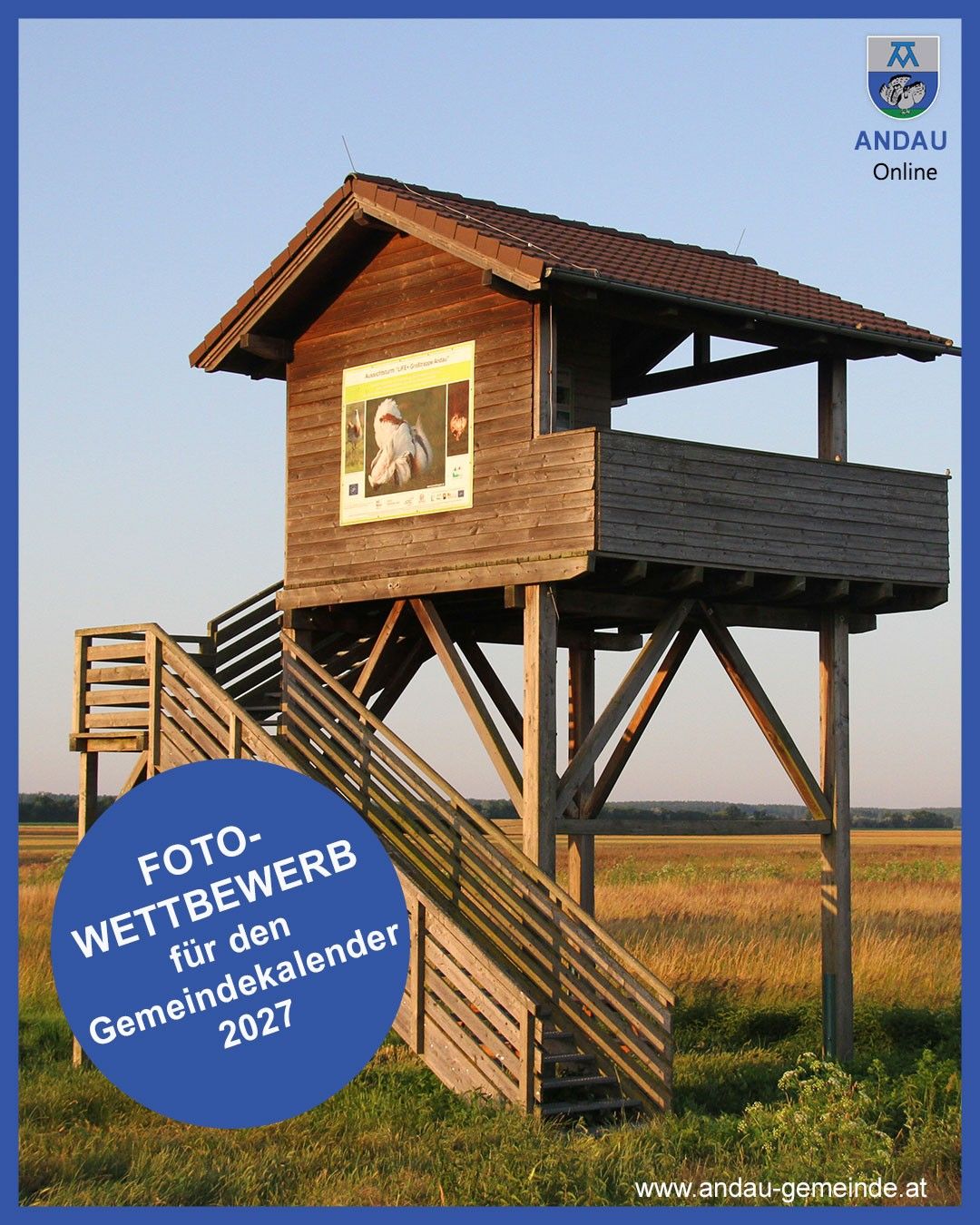 A wooden observation tower with a staircase leading to its entrance, a sign on its side, and a photograph of a white bird. The tower is located in a field. The text 'Foto-Wettbewerb für den Gemeindekalender 2027' is written on a blue circle.