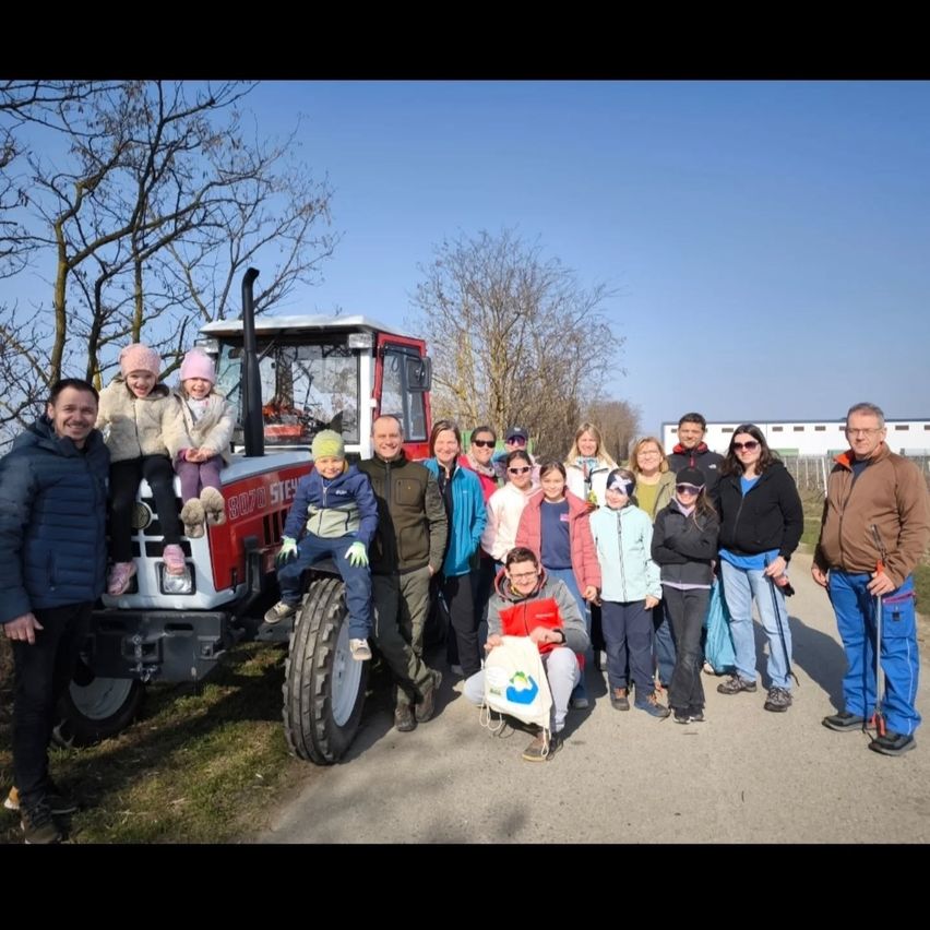Eine Gruppe von Menschen posiert für ein Foto mit einem roten Traktor, einige sitzen darauf, während andere stehen, alle in warmer Kleidung.