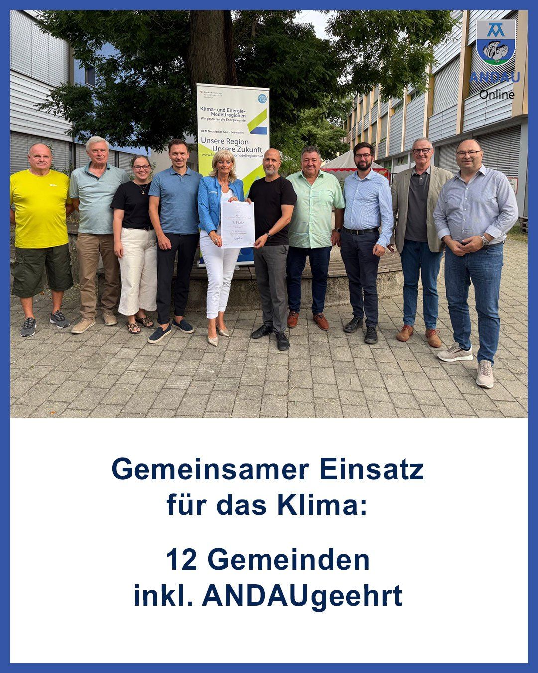 Eine Gruppe von Personen steht vor einem Banner mit Text auf Deutsch. Sie lächeln und scheinen für ein Foto zu posieren. Das Banner lautet 'Gemeinsamer Einsatz für das Klima' und '12 Gemeinden inkl. ANDAUgeehrt'.