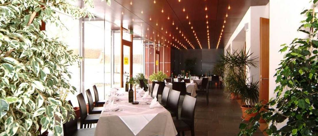 Bild enthält, Indoors, Dining Table, Furniture, Table, Building, Dining Room, Restaurant, Chair, Plant, Hall