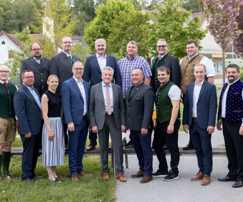 Eine Gruppe von Männern und einer Frau in formeller Kleidung stehen zusammen auf einem Außengelände, wahrscheinlich für ein Foto.