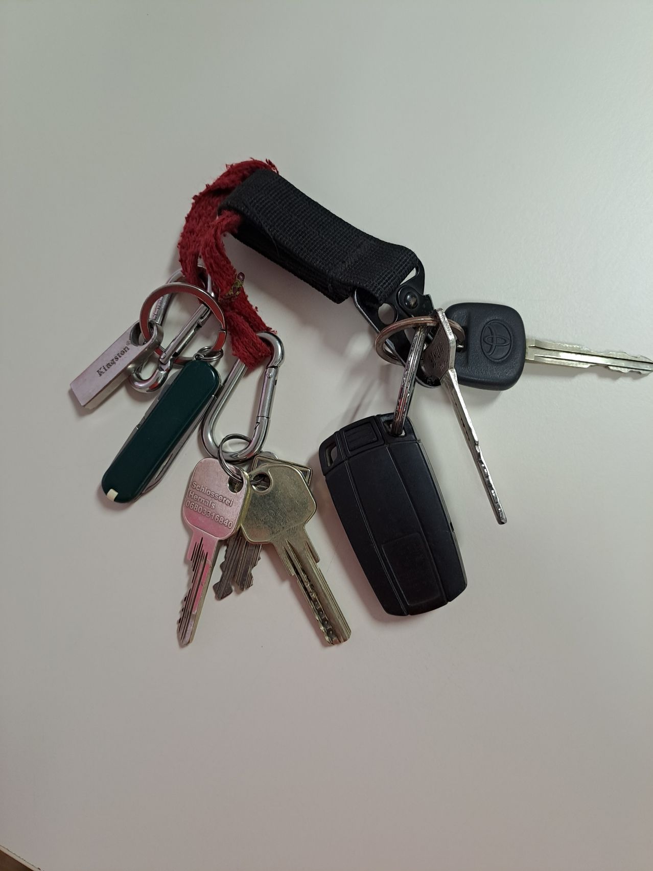 Ein Satz Schlüssel, einschließlich eines Autoschlüssels und eines Schlüssels mit einem USB-Stick, liegt auf einer weißen Oberfläche.