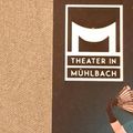Ein Poster mit braunem Hintergrund zeigt das Logo des Theaters in Mühlbach. Das Logo besteht aus einem stilisierten weißen Buchstaben M. Darunter steht in Weiß 'Theater in Mühlbach' geschrieben.