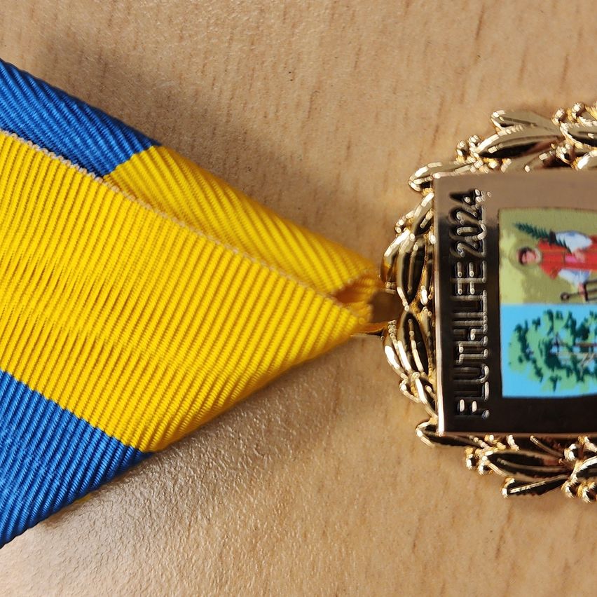 Bild enthält, Badge, Logo, Symbol, Clothing, Hat, Gold, Wristwatch