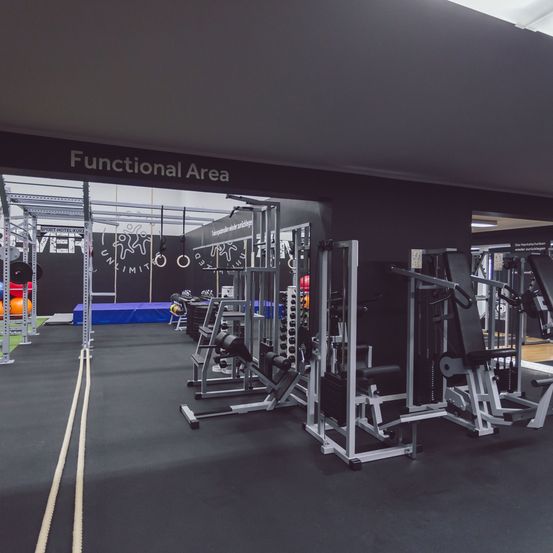Ein Fitnessstudio mit der Bezeichnung 'Functional Area' darüber, gefüllt mit verschiedenen Trainingsgeräten. Einige Bälle sind auf der linken Seite platziert.