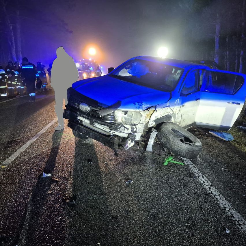Ein beschädigtes Fahrzeug steht nachts am Straßenrand. Rettungsdienste sind vor Ort, und das Auto hat einen Reifen verloren.