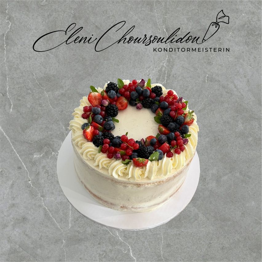 Ein weißer Kuchen mit Schlagsahne und verschiedenen Beeren, auf einer Marmorfläche präsentiert.