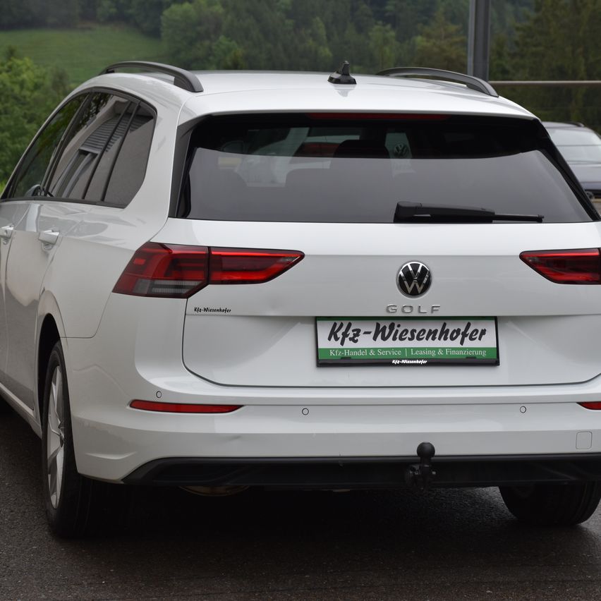 Die Rückseite eines weißen Volkswagen Golfs ist am Straßenrand geparkt und zeigt sein Nummernschild.
