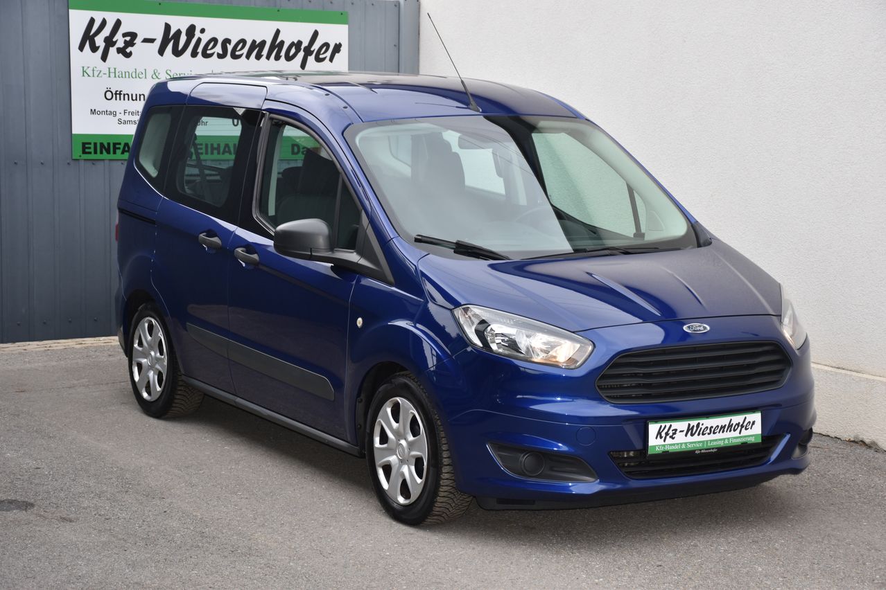 Ein blauer Ford Transit Connect ist vor einem Gebäude geparkt. Das Fahrzeug hat ein Nummernschild mit der Aufschrift Kfz-Wiesenhofer.