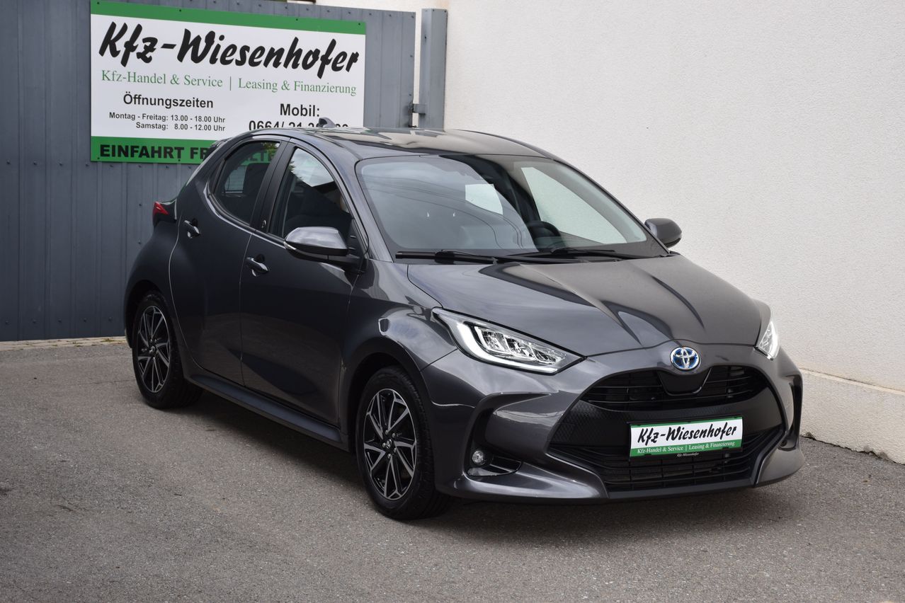 Ein schwarzer Toyota-Wagen steht vor einer weißen Wand mit einem Banner. Das Banner hat Text und Zahlen, und das Auto hat ein Nummernschild.