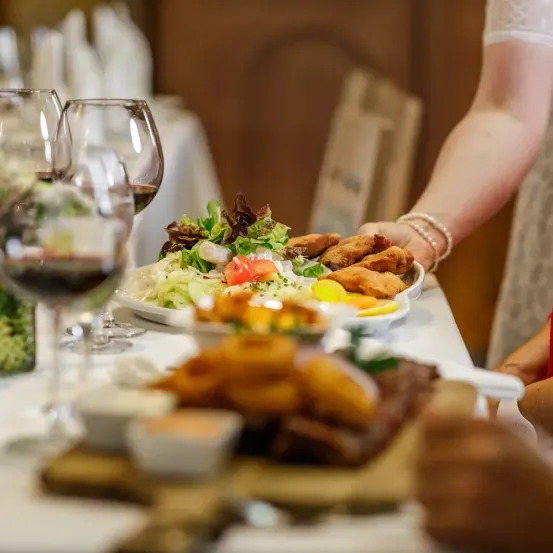 Ein Tisch für ein Essen mit Salat, frittierten Speisen, Wein und Brot.