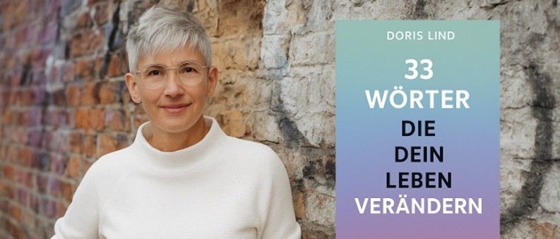 Eine Frau mit kurzem weissem Haar und Brille trägt ein weisses Rollkragenshirt und steht neben einem Buch mit dem Titel '33 Worte, die dein Leben verändern können'.