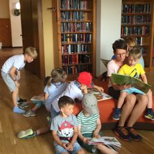 Bild enthält, Shelf, Wood, Book, Library, Person, Reading, Flooring, Hardwood, Couch, Shoe