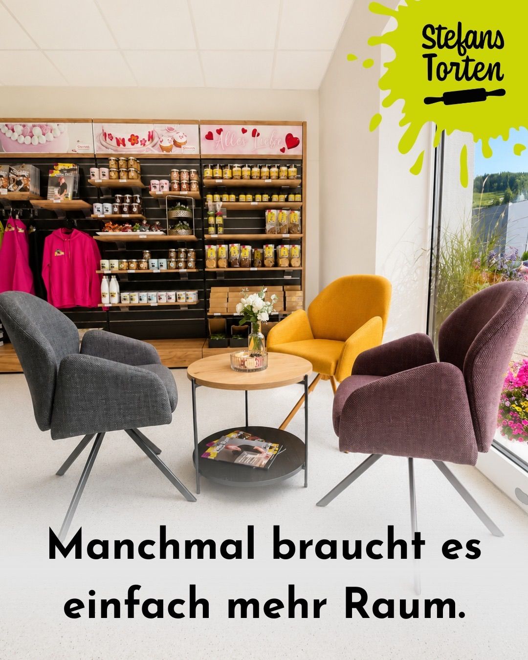 Ein gemütlicher Raum mit drei Stühlen um einen Tisch, einem Holzregal voller verschiedener Gegenstände und einem Fenster mit Blick auf einen Garten. Der Text 'Manchmal braucht es' wird unten angezeigt.
