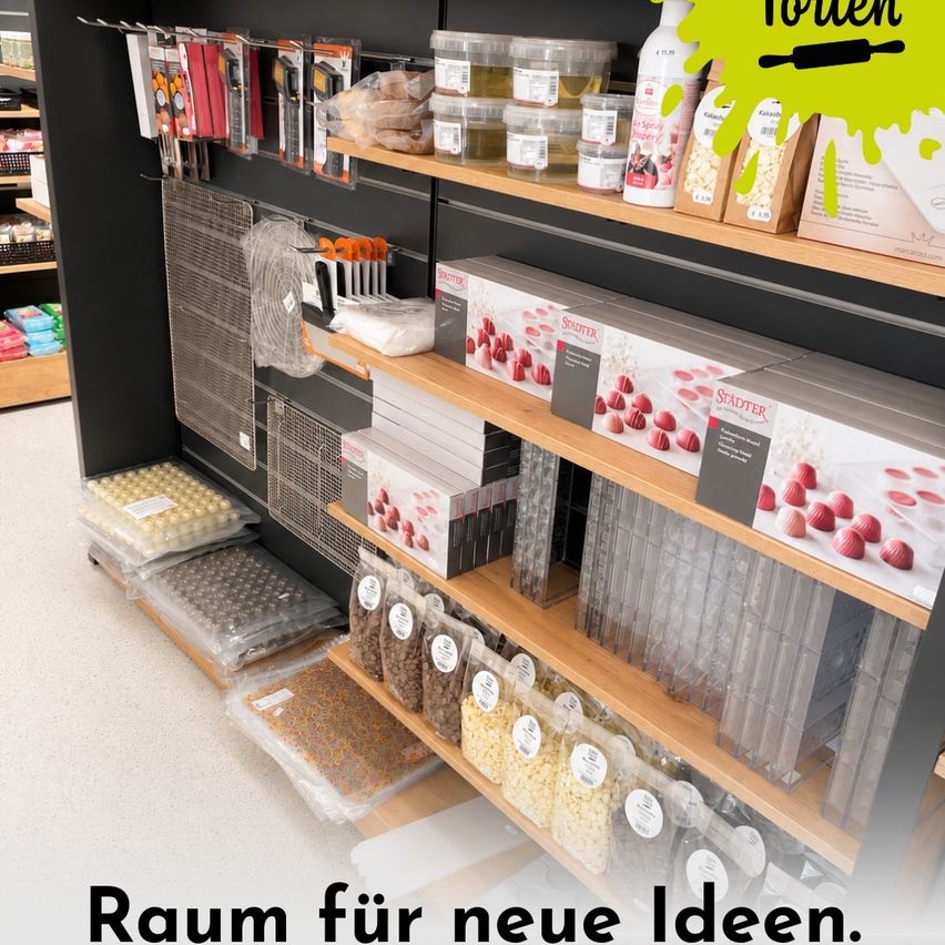 Ein Bäckereibedarfsladen mit Regalen voller Backwerkzeuge, Zutaten und Behältern. Die Regale sind mit verschiedenen Artikeln gefüllt, einschließlich Plastiktüten, Kartons und Behältern. Der Laden hat ein sauberes und organisiertes Erscheinungsbild.