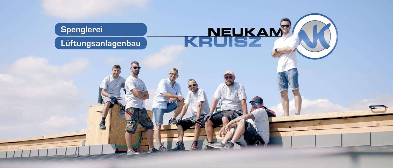 Eine Gruppe von Männern, alle in weißen Hemden gekleidet, posiert für ein Foto auf einem Dach. Ein Mann steht, die anderen sitzen. Hinter ihnen steht ein Schild mit der Aufschrift 'NEUKAM KRUISZ'.