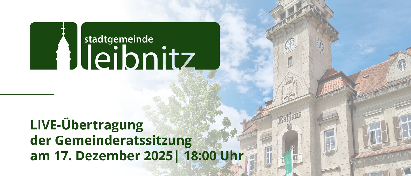 Das Bild zeigt eine Stadtratssitzung im Dezember 2025 um 18:00 Uhr. Im Hintergrund befindet sich ein Uhrturm mit Flaggen und einem Baum.