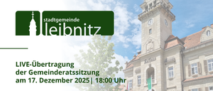 Das Bild zeigt eine Stadtratssitzung im Dezember 2025 um 18:00 Uhr. Im Hintergrund befindet sich ein Uhrturm mit Flaggen und einem Baum.