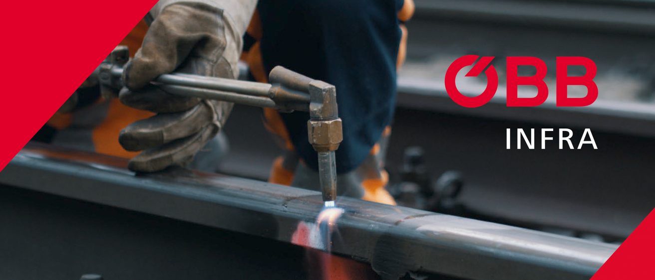 Eine Hand in einem Arbeitshandschuh hält ein Metallwerkzeug, möglicherweise ein Schraubenschlüssel, vor einem roten Hintergrund.