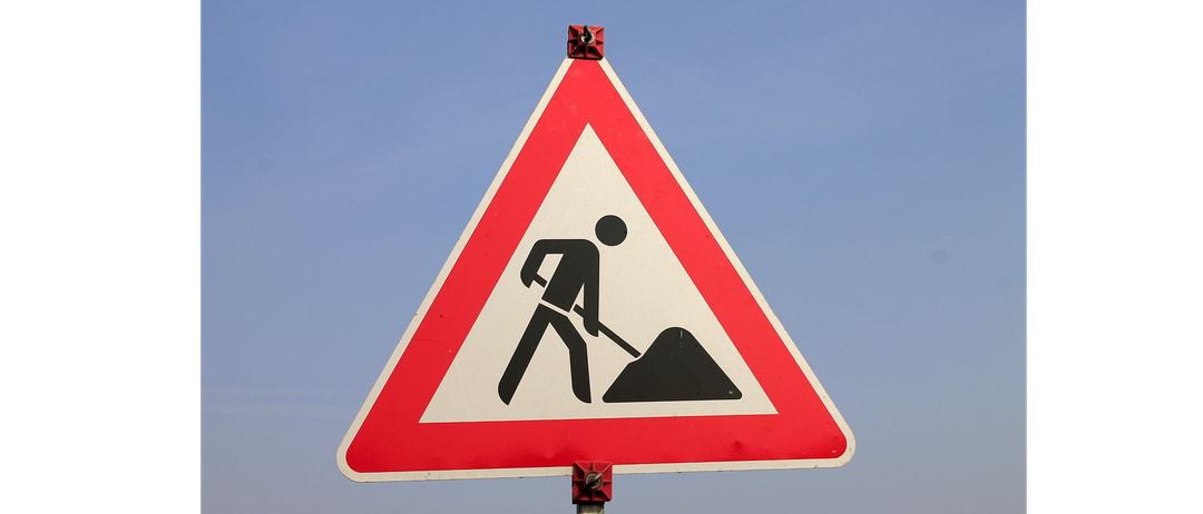 Ein dreieckiges Verkehrsschild mit einem Mann, der in der Mitte gräbt. Das Schild ist rot mit weißen Rändern.