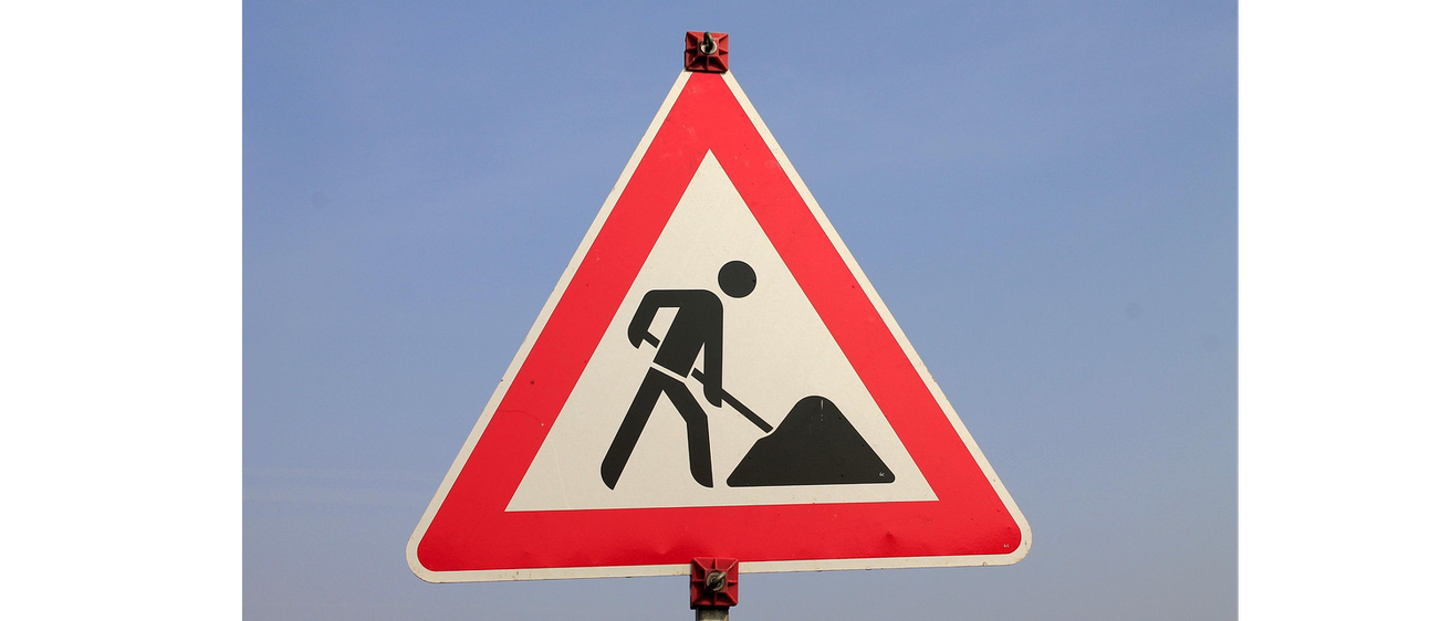 Ein dreieckiges Verkehrsschild mit einem Mann, der in der Mitte gräbt. Das Schild ist rot mit weißen Rändern.