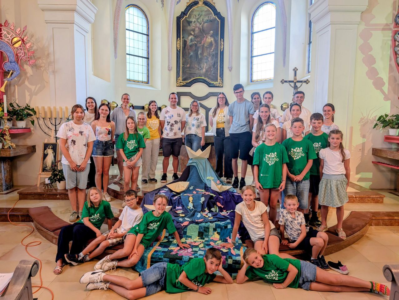 Kinder und Jugendliche in grünen T-Shirts und Sommerkleidung in einer Kirche in Österreich