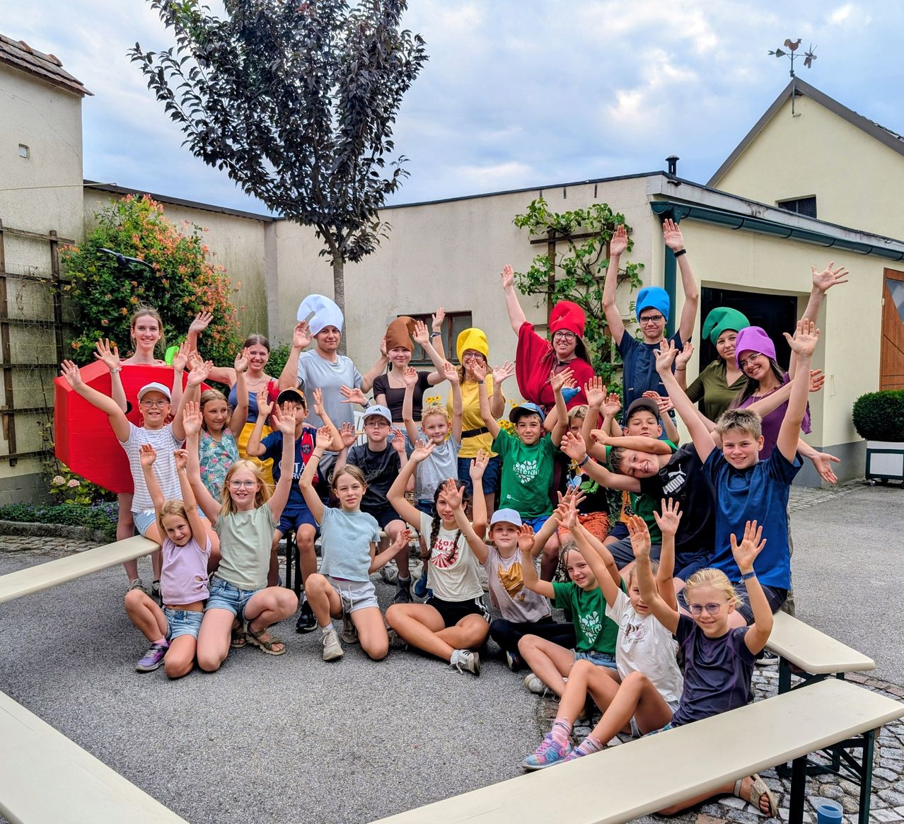 Eine Gruppe von Kindern und Erwachsenen mit bunten Hüten und lächelnd, posiert für ein Foto im Freien.