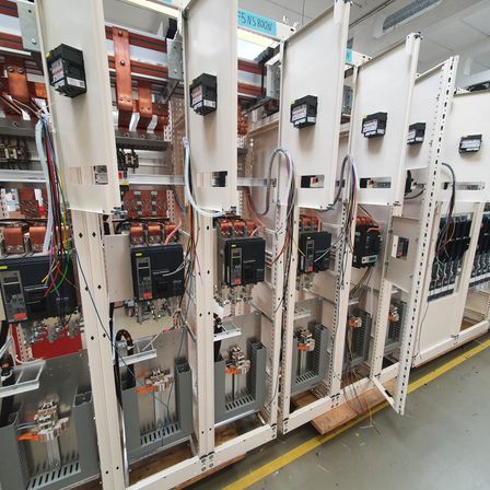 Industriemaschinen mit zahlreichen Drähten und Komponenten sind in einer Fabrikumgebung ausgestellt, mit Etiketten und Geräten an den Wänden montiert.