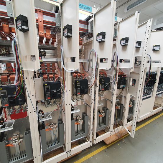 Industriemaschinen mit zahlreichen Drähten und Komponenten sind in einer Fabrikumgebung ausgestellt, mit Etiketten und Geräten an den Wänden montiert.