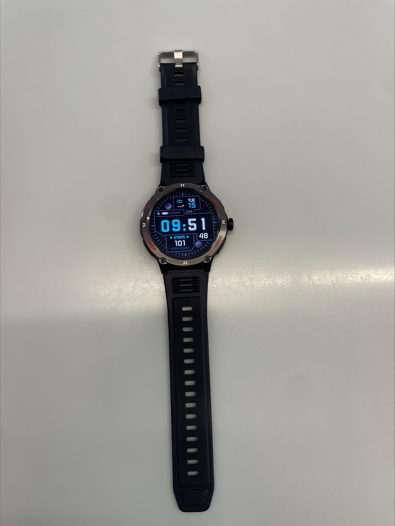 Eine schwarze Smartwatch zeigt die Zeit 09:51 an, mit 101 gezählten Schritten. Das Datum ist Dienstag, der 15.