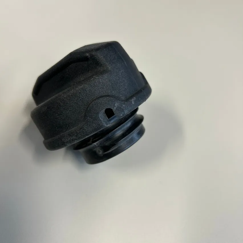 Ein schwarzer Plastikdeckel mit einem kleinen Loch in der Mitte, möglicherweise ein Teil eines mechanischen Geräts.