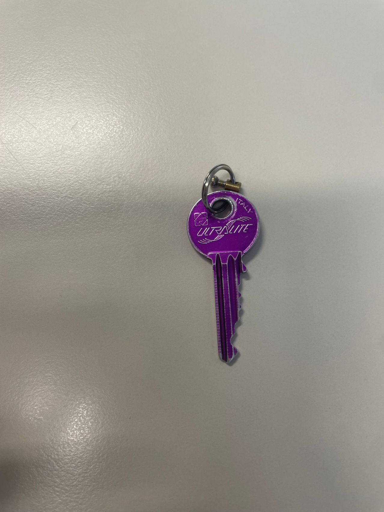 A purple key with the word Ultralite written on it, attached to a silver keyring.