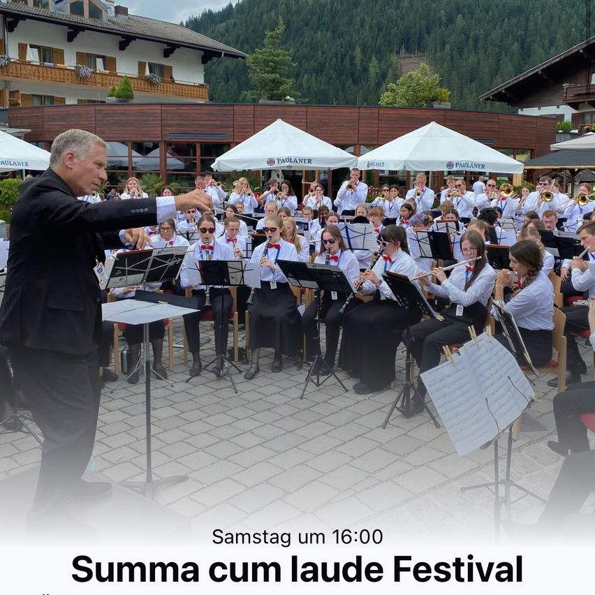 Ein Orchester spielt auf der Bühne, angeführt von einem Dirigenten. Sie spielen verschiedene Instrumente, und der Text darunter sagt Samstag um 16:00 Uhr. Summa cum laude Festival.