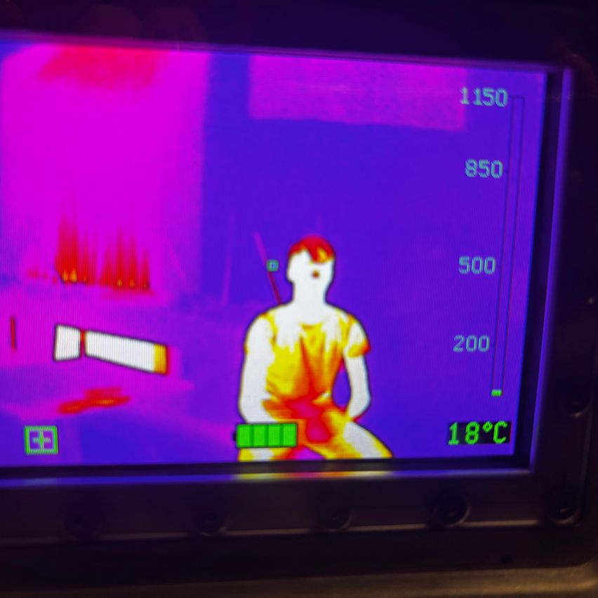 Ein Thermobild zeigt eine Person in einem gelben Kleid, wobei eine Temperatur von 18°C auf dem Bildschirm angezeigt wird.