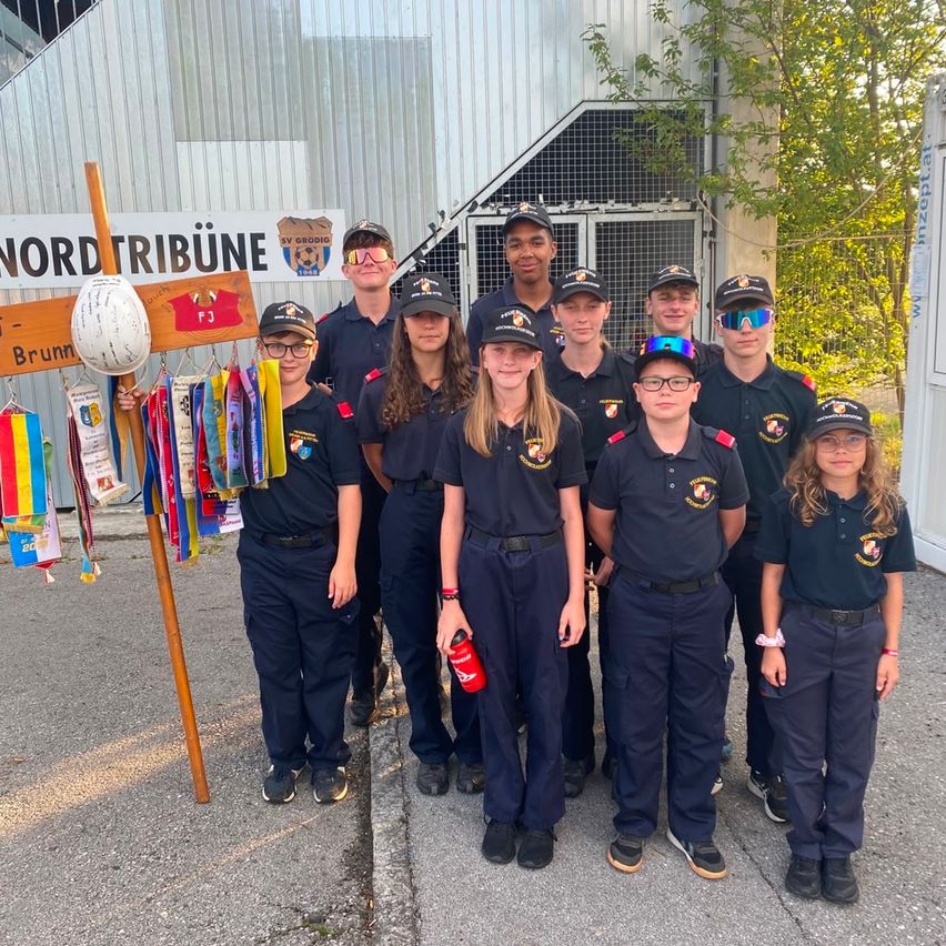 Jugendfeuerwehrjugendliche in Uniform posieren vor der Nordtribüne in Grodig.