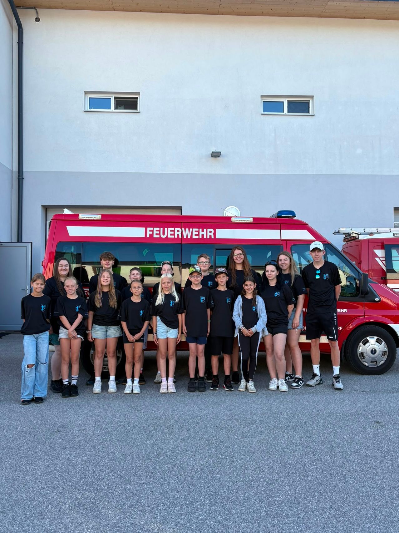 Jugendfeuerwehr vor rotem Feuerwehrauto mit Schriftzug FEUERWEHR