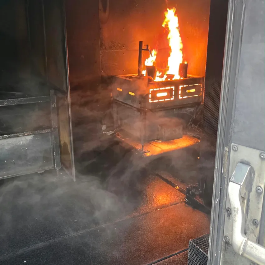 Ein Feuer brennt in einem industriellen Ofen mit Rauch, der aus ihm kommt.