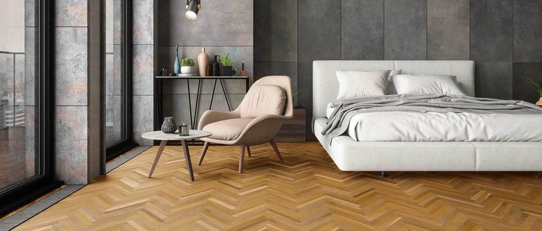 Ein modernes Schlafzimmer mit einem weißen Bett und einem Stuhl auf einem hölzern gemusterten Boden, grauen Wänden und einem Tisch mit Pflanzen.