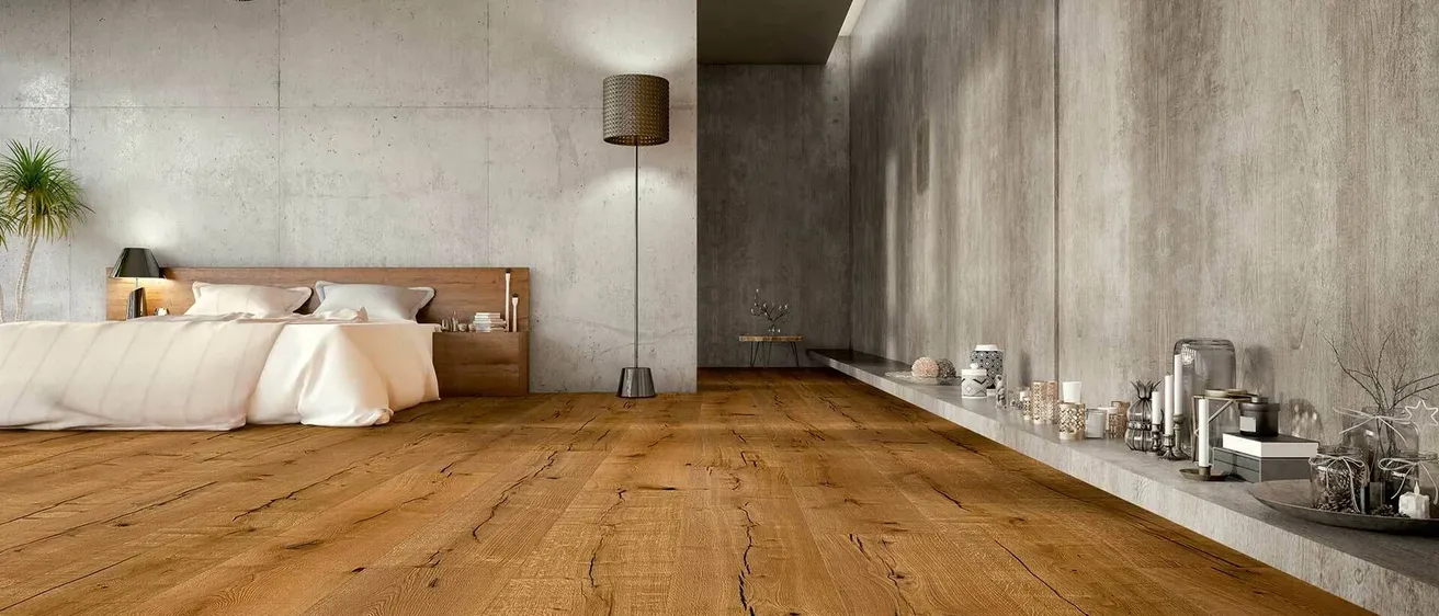 Ein modernes Schlafzimmer mit Betonwänden, Holzboden, einem Bett, Kissen, einer Lampe und einem Regal mit verschiedenen Gegenständen darauf.