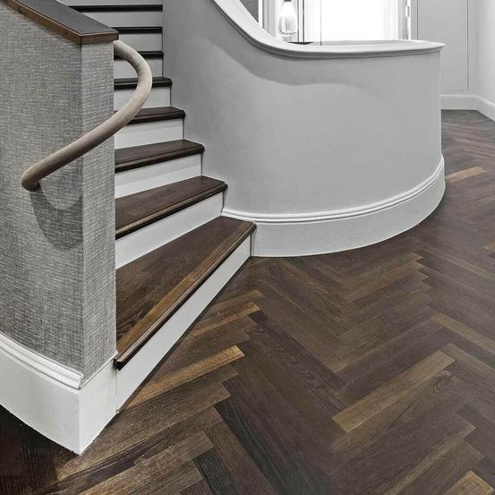 Eine moderne Treppe mit Holzstufen und einem weißen Handlauf, der zu einem Raum mit weißen Wänden und einem weißen Holzgeländer führt.