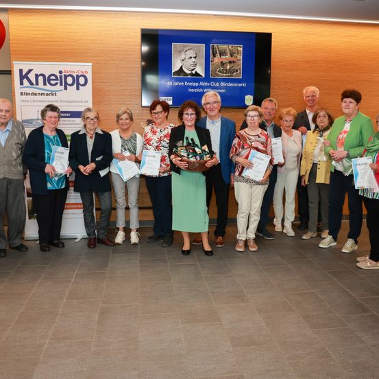 Eine Gruppe von Menschen, die Urkunden halten, steht vor einem Banner. Sie lächeln und posieren für ein Foto.