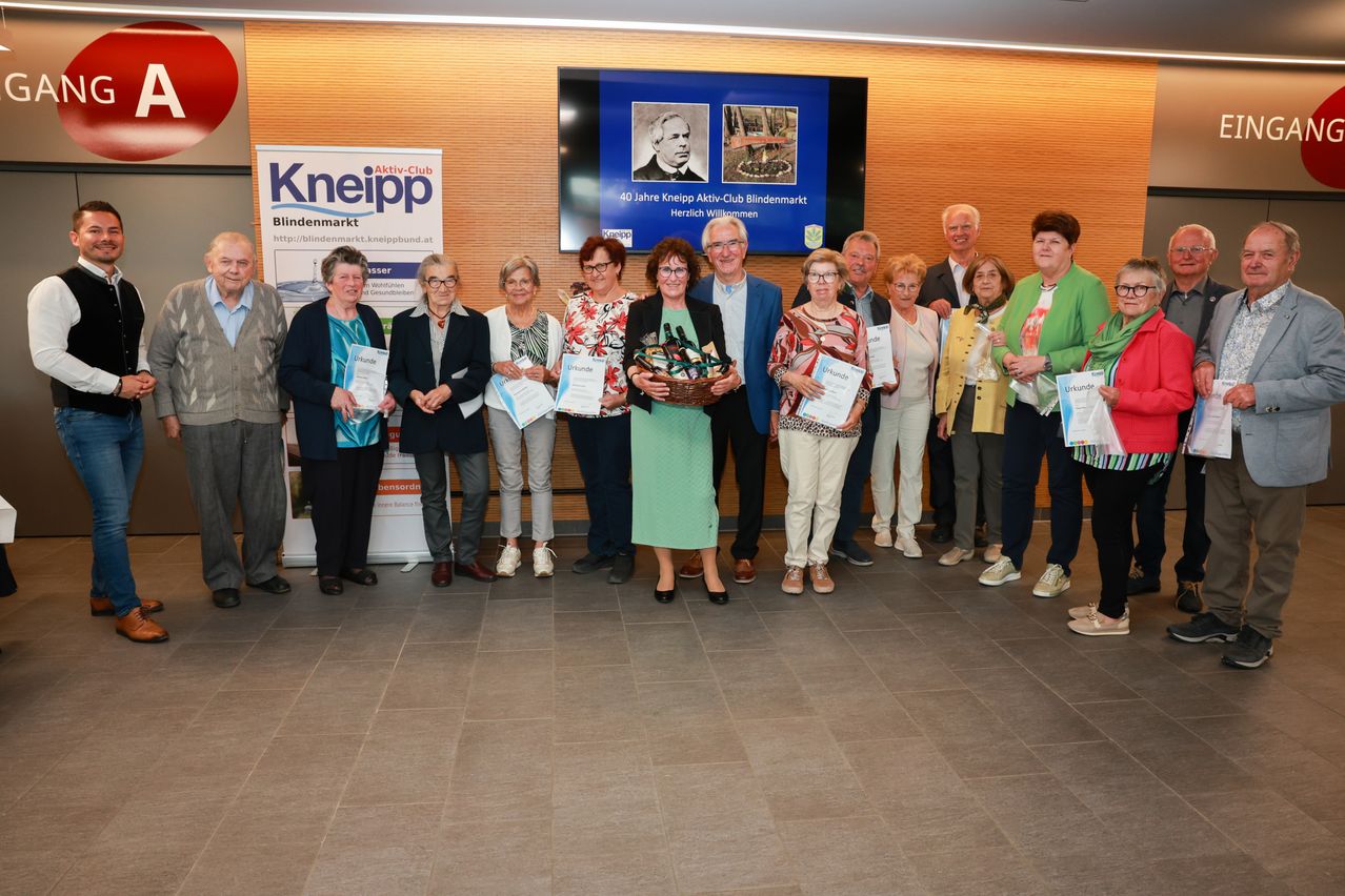 A group of people are standing together, possibly posing for a photograph. They are holding certificates and some are holding baskets.