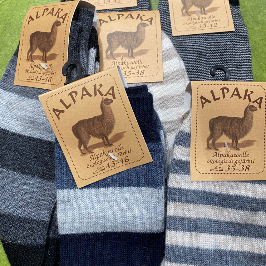 Eine Reihe von blau-weiß gestreiften Socken aus Alpakawolle. Jedes Etikett hat ein Bild eines Alpakas und Größenangaben.