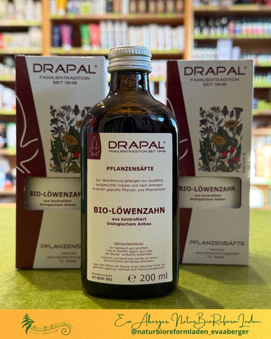 Eine Flasche Bio-Lowenzahn-Pflanzenextrakt von Drapal steht vor zwei Kartons auf einem Tisch. Die Flaschen und Kartons sind mit Bio-Lowenzahn beschriftet und haben botanische Illustrationen.