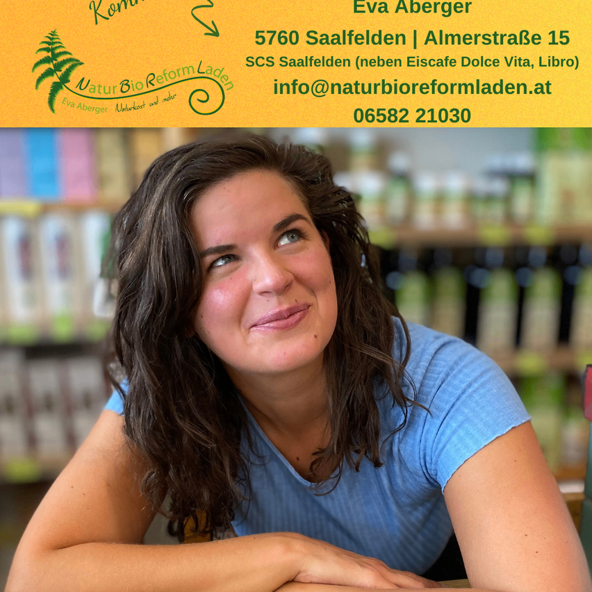 Eine lächelnde Frau mit langen Haaren sitzt in einem Geschäft und trägt ein blaues Shirt. Hinter ihr ist ein Bücherregal zu sehen. Eine Überlagerung zeigt Eva Abergers Kontaktdaten.