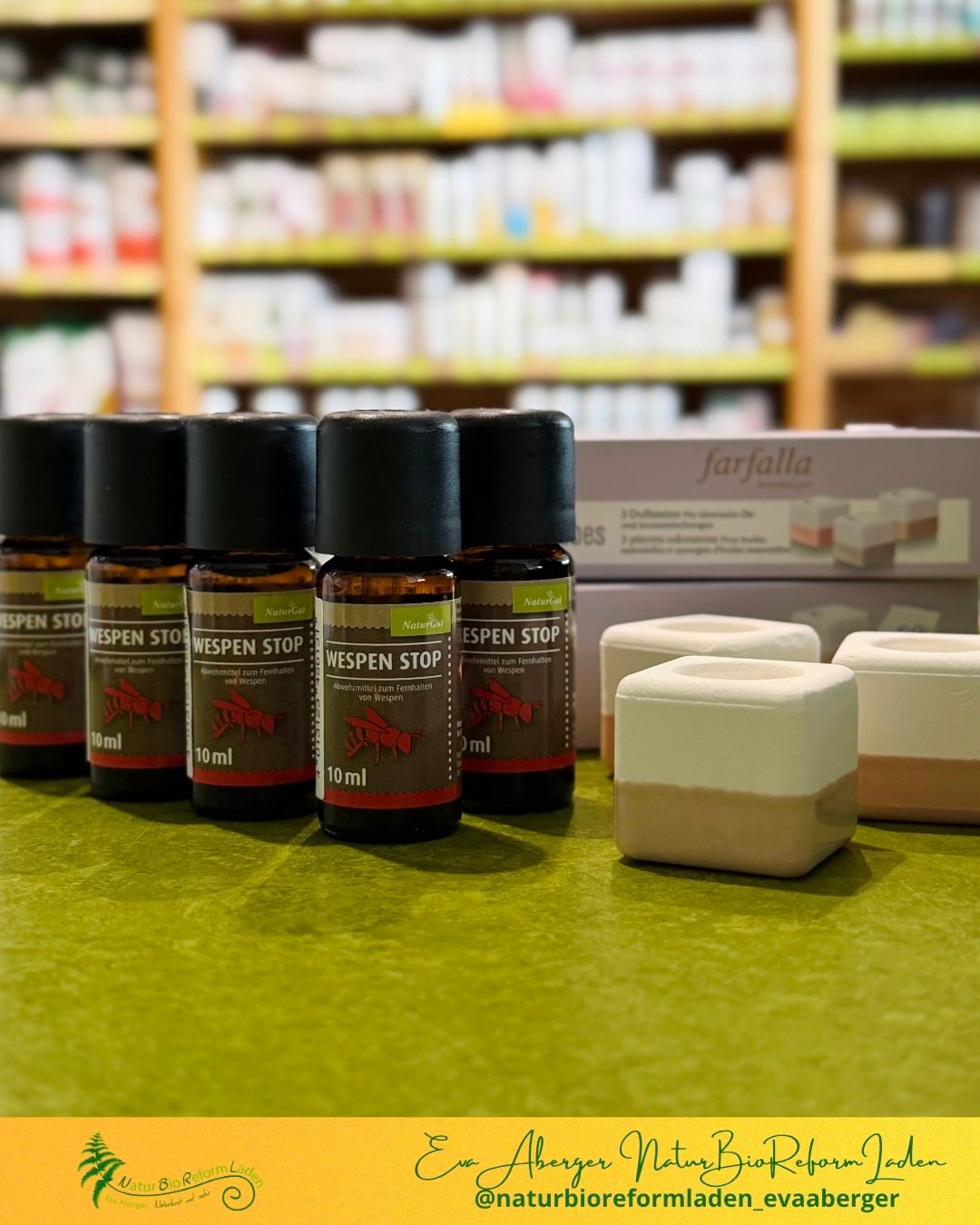 Five bottles of Wespen Stop, a natural wasp repellent, are displayed on a green surface with a blurry background of a store.