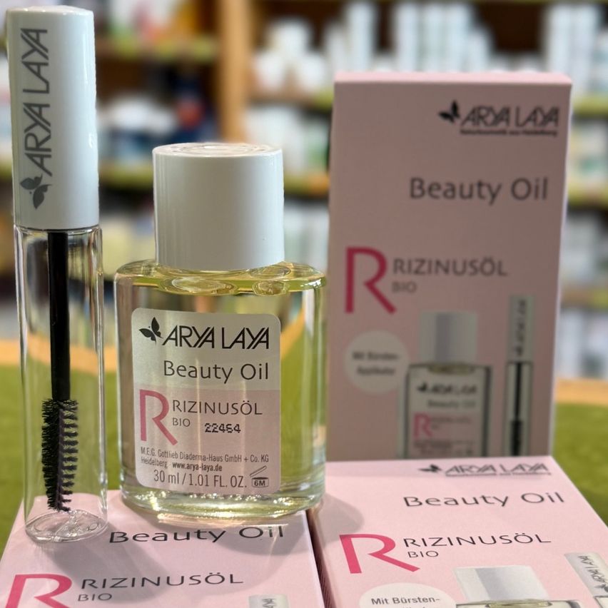 Ein Nahaufnahme einer Flasche Arya Layla Beauty Oil mit einem Wimperntusche-Applikator und einer rosa Box im Hintergrund.