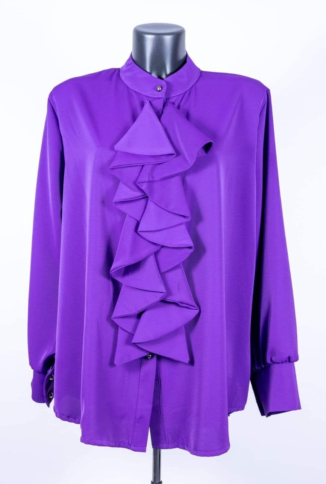 Ein lila Hemd mit gerüschter Krawatte und langen Ärmeln, das auf einem weißen Hintergrund präsentiert wird.