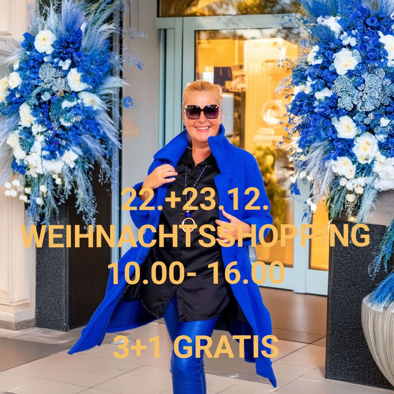 Eine lächelnde Frau in einem blauen Mantel steht vor blauen und weißen Blumendekorationen. Der Text-Overlay lautet 'Weihnachtsshopping 22+23.12. 10.00-16.00 3+1 gratis'.