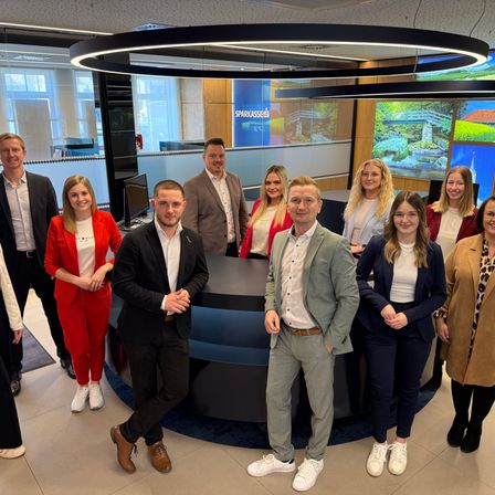 Eine Gruppe von Menschen posiert fur ein Foto in einem Buro. Das Buro hat ein modernes Design.